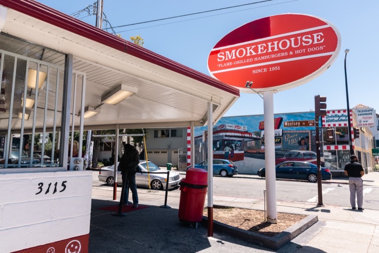 Smokehouse's red oval sign and covered patio on a sunny day